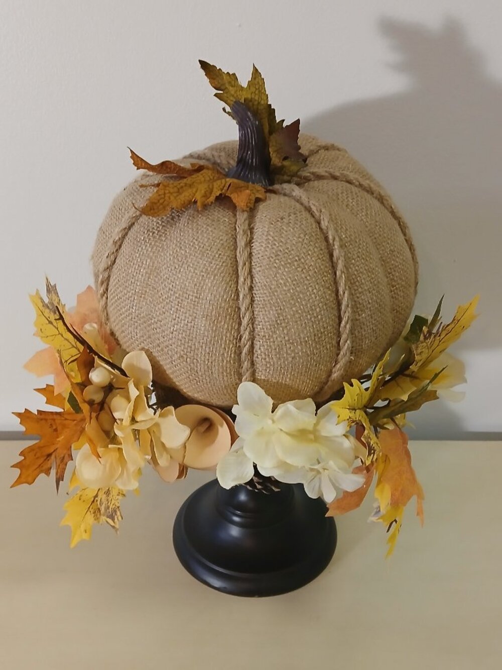 Burlap pumpkin on pedastel with fall leaves and flowers